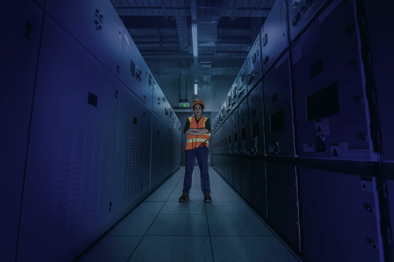 Technicienne en gilet de sécurité dans un couloir de cellules électriques